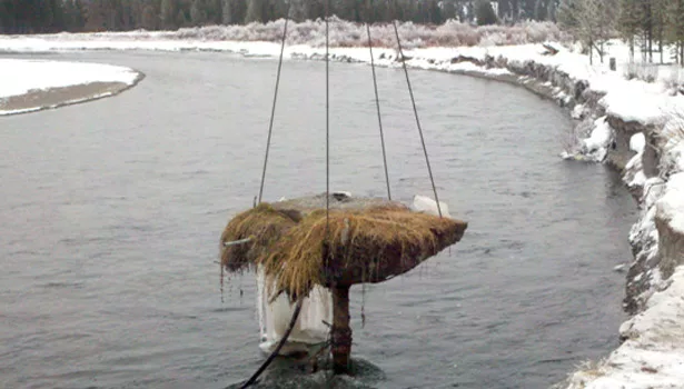 A crane prepares to pull the well top and its tiny island from the Madison River