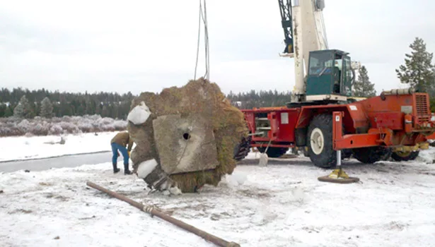 A workman unhooks the top casing of the well