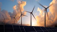 An image of a sunset, wind turbines, and solar panels.