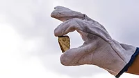 An image of a miner holding up a gold nugget