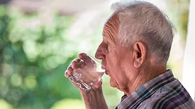 A senior drinking water from a cup
