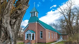 An image of a church with a green roof and brick