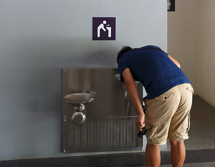 Man drinking water at fountain.