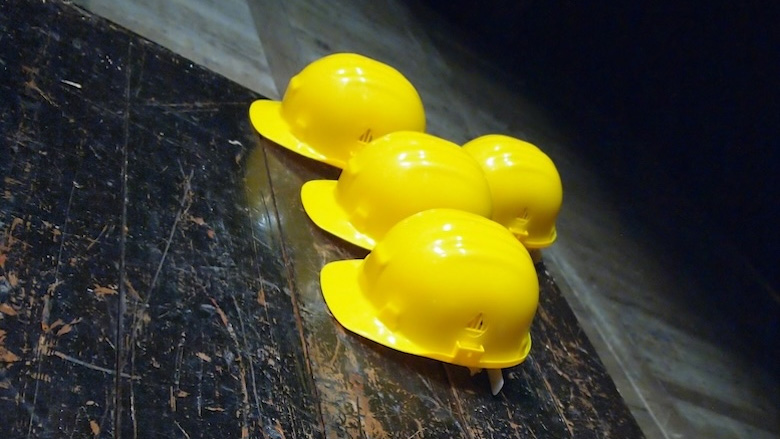 Four hard hats placed on a dark floor