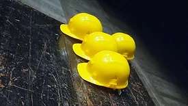 4 construction hard hats on a dark floor