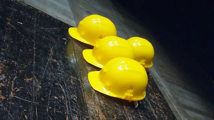 4 construction hard hats on a dark floor