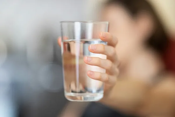 Woman puts a glass of water into focus