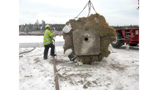 workman unhooks the top casing of the well